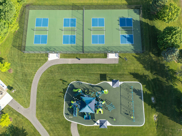 Overhead view of a new playground and four new pickleball courts