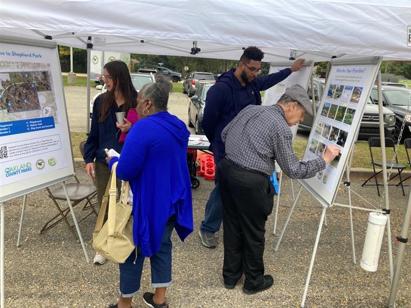 four people talking and interacting with a priorities board during an open house event
