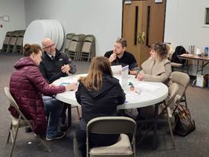 five people sitting around a table engaged in conversation
