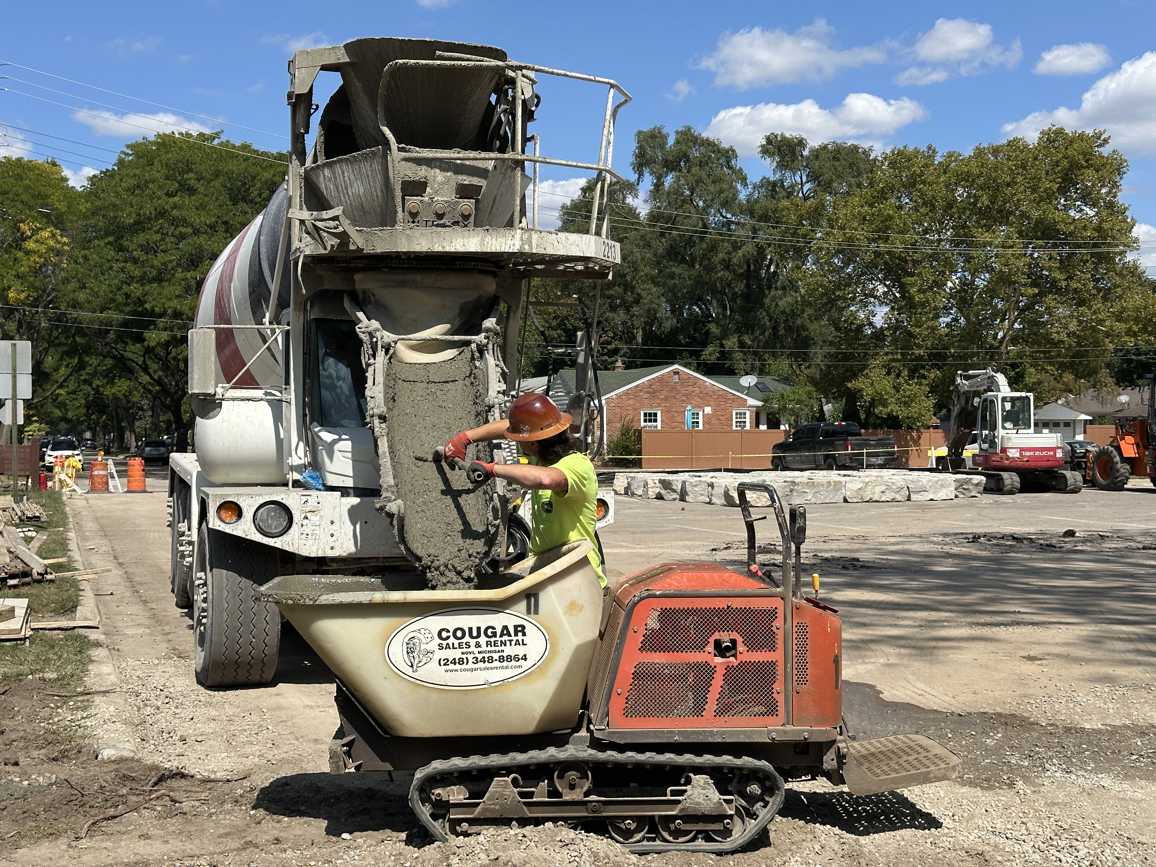 a construction worker unloading concrete mix from a truck to pave a parking lot
